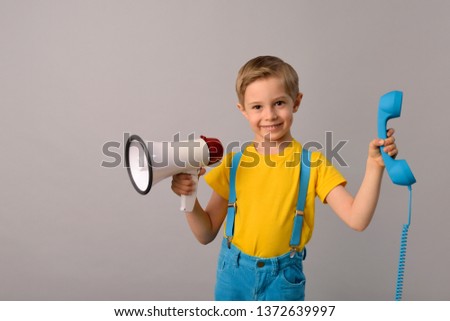 small, smiling boy is holding a phone