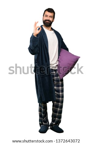 Man with beard in pajamas showing ok sign with fingers over isolated white background