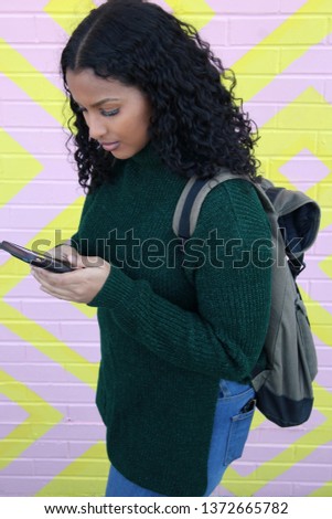 College student on her way to school carrying a back pack while texting on cell phone. Royalty-Free Stock Photo #1372665782