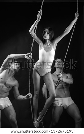 Acrobat with rope on black background has fit and muscular body