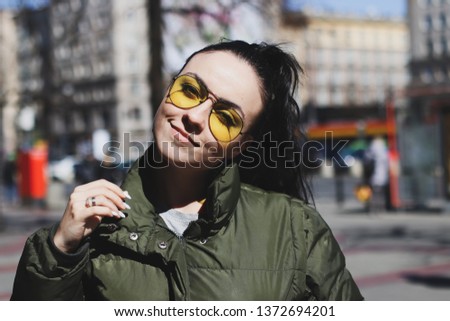 young beautiful girl with yellow glasses on a city street on a sunny day