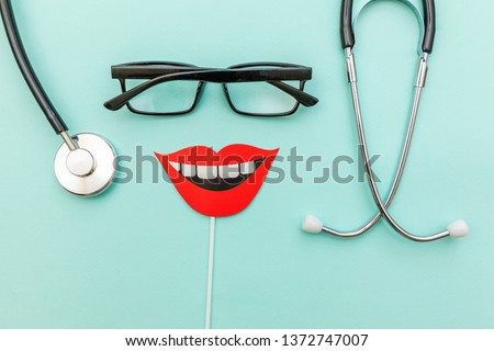 Health dental care concept. Medicine equipment stethoscope or phonendoscope glasses sign of smile teeth isolated on trendy pastel blue background. Instrument device for dentist doctor