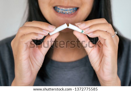 Woman hands destroying or crushing cigarette and blurred smiling face,Concept no smoking day world quitting world no tobacco in 31 may day,Close up