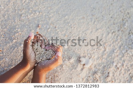 Child girl holding sand make heart shape in hands and playing on the beach in summer vacation