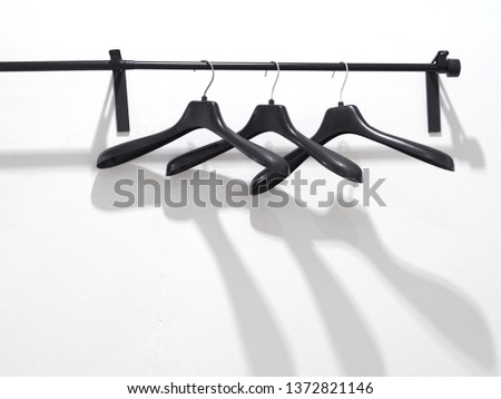 Close up black plastic hanger on the rack over white wall at fitting room.