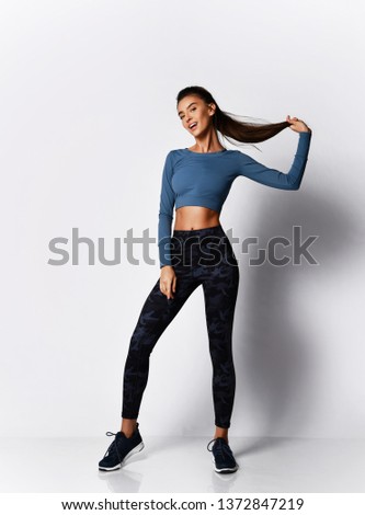 Slim brunette woman runner sprinter before  workout exercise in sport wear on gray background