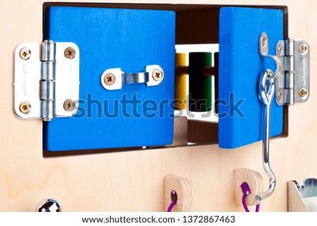 Close-up of a blue padlock with a key on a wooden busy board- educational toy for children, babies on a white isolated background. A toy for entertaining children and resting parents
