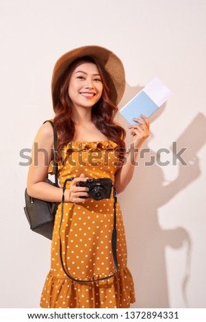 Expressive tourist woman in summer casual clothes, hat holding passport, tickets isolated on beige background. Female traveling abroad to travel weekends getaway. Air flight journey concept