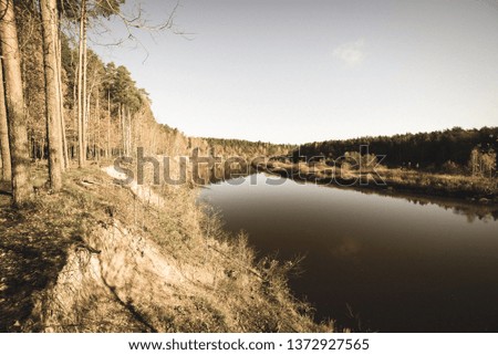 blue sky and clouds reflecting in calm water of river Gauja in latvia in autumn. walk on the shore of riverbank. clear fall day. wide angle view - vintage retro look