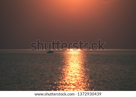 dramatic red orange colored sunset over the calm sea at summer with sun way of reflections in water - vintage retro film look