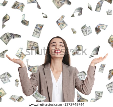 Happy young businesswoman under rain of money on white background