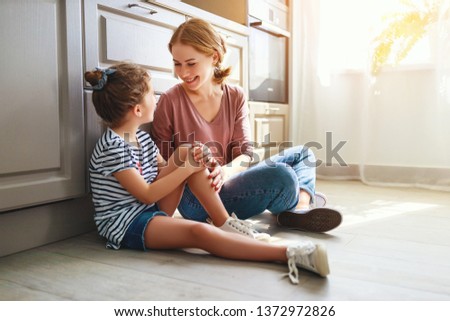 happy mother's day! family mother and child daughter hugging in kitchen on floor
