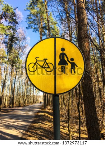 traffic sign pedestrian - bicycle path with the division of transport.  road sign on a yellow background standing in the park