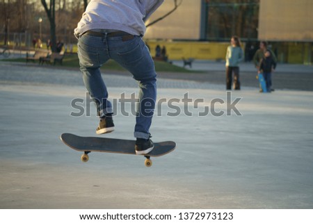 Image of skateboarders'l legs and skate. Skateboarder doing the trick