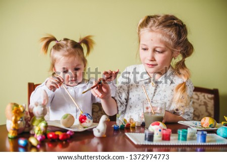 Two little sisters painting color the eggs until the day of the Easter