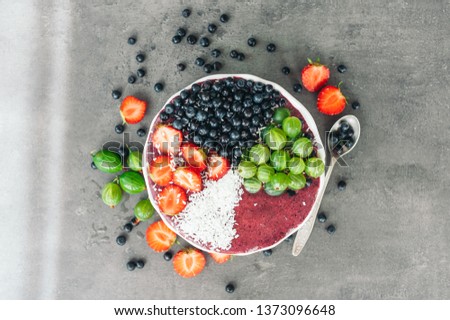 Ripe fruit on bowl. Strawberry, gooseberry and blueberry decorated with coconut flakes. High resolution product. Spoon with berries