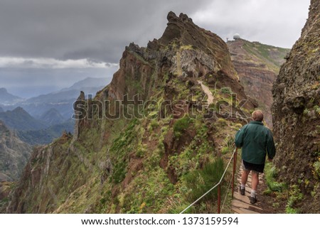 Senior tourist in the mountains of Madeira at Pico do Areeiro (Arieiro), while hiking to Pico Ruivo on a cloudy summer day with ominous sky and storm weather