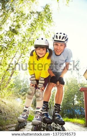 portrait of a sports dad and daughter in a helmet. Dad with his little daughter on the skates. family rollerblade