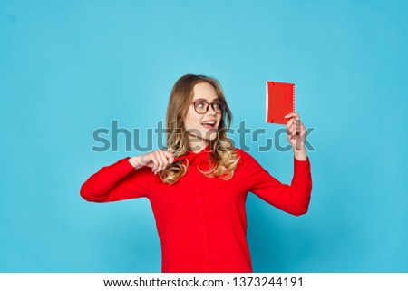 Business woman in a red shirt with a notepad in hand blue isolated background