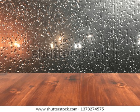 Empty top of wood coffee table with drop on window in rainy night city