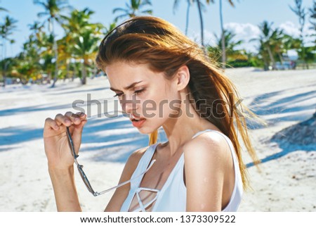 A pretty woman in a white bathing suit holds glasses in her hands the rest is exotic