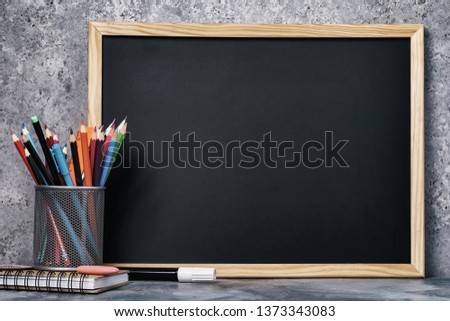 A set of various pencils, pens and a chalk board with copy space