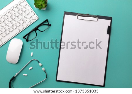 Stethoscope in doctors desk with tablet, pen, keyboard, mouse and pills. Top view with place for your text.
