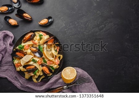 Spaghetti vongole, Italian seafood pasta with clams and mussels, in plate with herbs on rustic stone background. Traditional Italian sea cuisine, close-up, top view. Copy space