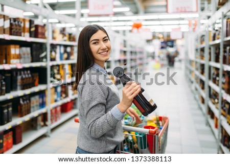 Woman with bottle of alcoholic beverage in shop