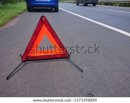 Emergency red warning triangle on the road sign with the white road line and blue broken car