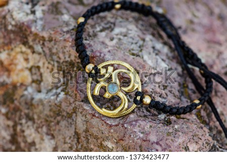 Metal om symbol macrame bracelet on natural rocky background