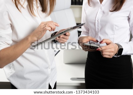 Theme business women. Two young Caucasian women business partners in formal clothes sign a contract, making a deal a handshake in the office. Teamwork.