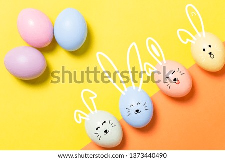 colorful pastel easter eggs on yellow and orange background with copy space