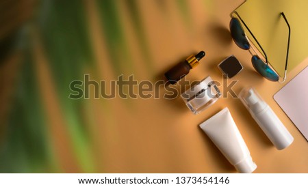 Flat lay, top view workspace with sun glasses, hat, sun block, blank label cosmetic packaging on yellow background. Summer stylish traveller blogger concept.