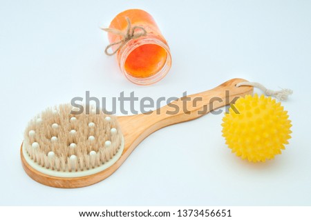 Massage brush and massage yellow ball with spikes for the body and scrub in a jar close-up on a white background. Anti-cellulite body massagers. Body care at home.