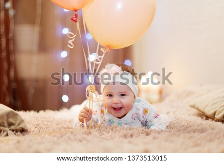 Cute little girl with ballons sittimg on bed. Happy birthday, five mouth old baby - Image