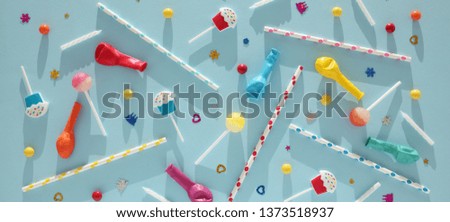 Kids birthday party decoration, blue background (pattern). Colorful candies, bright balloon, festive candles, and paper straws.