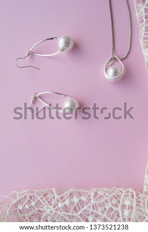 Beautiful silver shiny pearl jewelry, trendy glamorous earrings, chain on pink purple background with exquisite lace. Lay Flat, top vertical frame