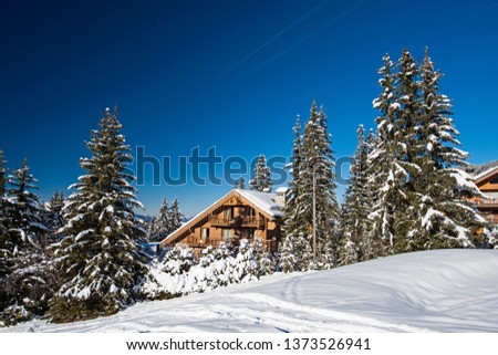 Panoramic view of snow covered trees in an alpine ski resort with apartment buildings on slope