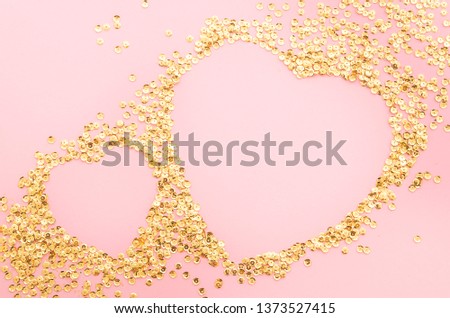 Top view two hearts shaped from golden sparkles on pink background. Romantic concept with copy space.