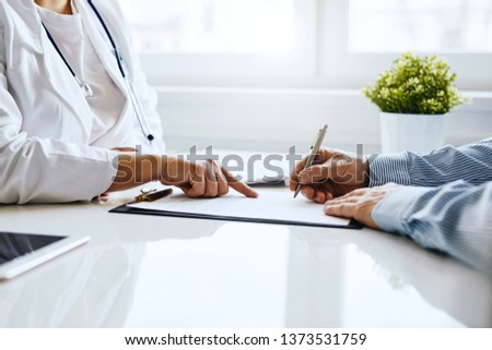 Patient signs a document with his doctor in medical office Royalty-Free Stock Photo #1373531759