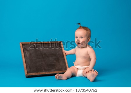 baby girl in diapers holding a drawing Board on a blue background