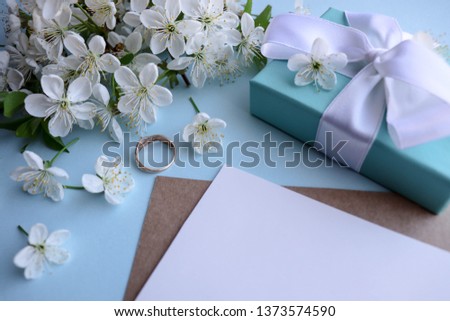 Wedding invitation card design. white flowers, wedding ring and envelope on a blue background
