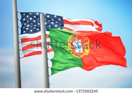 Flags of Portugal and the USA against the background of the blue sky