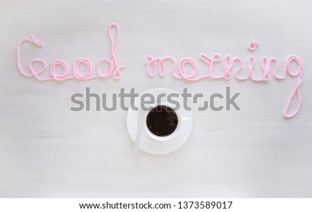 the inscription "good morning" pink thread on a white table with a cup of coffee