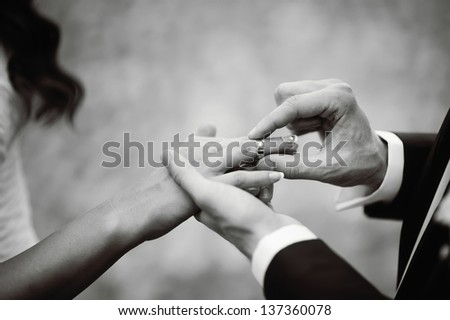 Marry me today and everyday, hands of a wedding heterosexual couple. Groom put a ring on finger of his lovely wife.  Royalty-Free Stock Photo #137360078