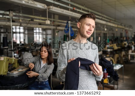 close up photo of a young man analyzing a piece of work and a woman working with linking machine for knitting in textile industry