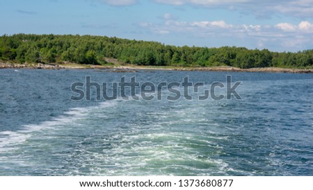 Water splash from moving boat and small island with green forest