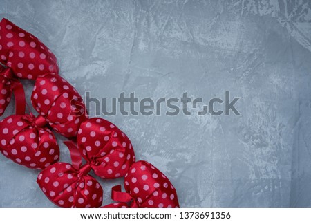 Red polka dot bows. Plush bow A toy. Light background under the concrete. Space for text.