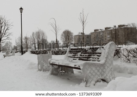 Snow covered wooden bench in the alley in the Park